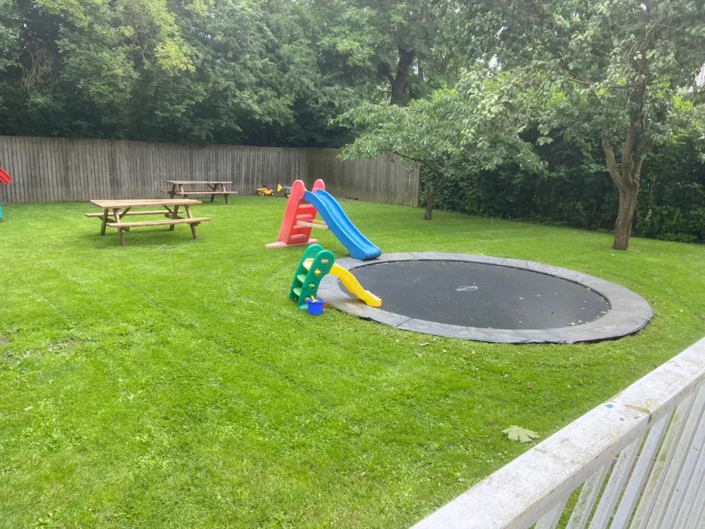 Fællesareal med nyslået græs, legeplads og trampolin