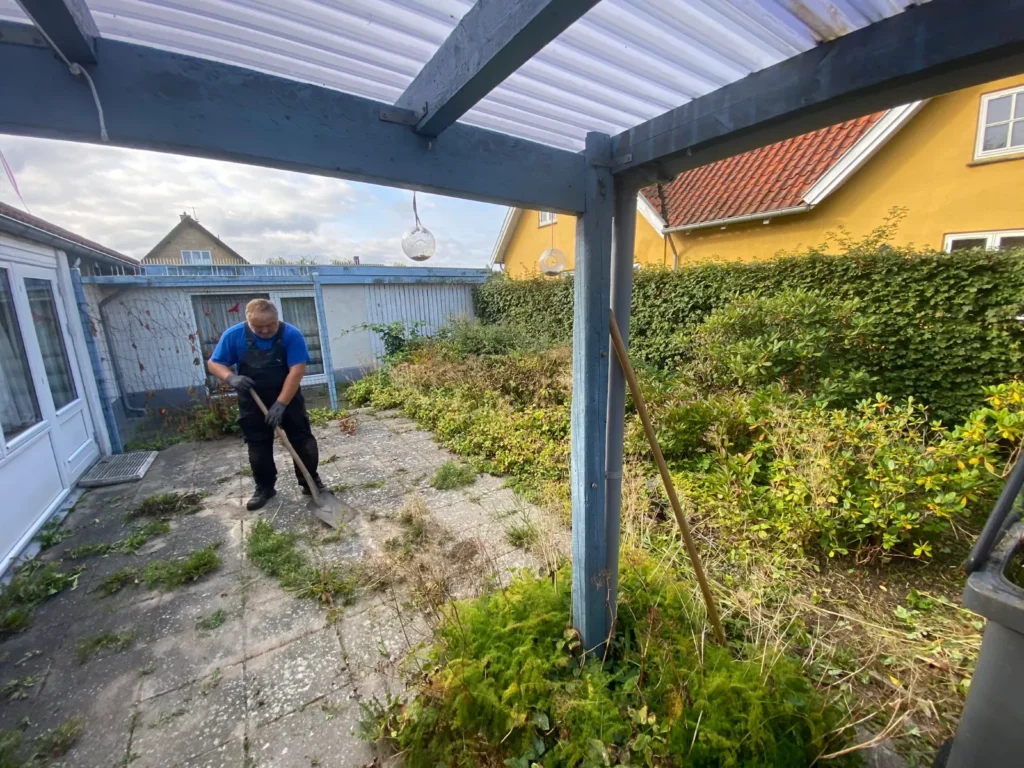 Havemand fjerner ukrudt ved overdækket terrasse