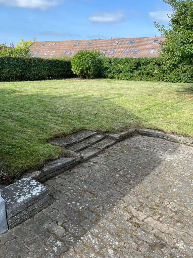 Græsplæne med trappe og flisebelægning