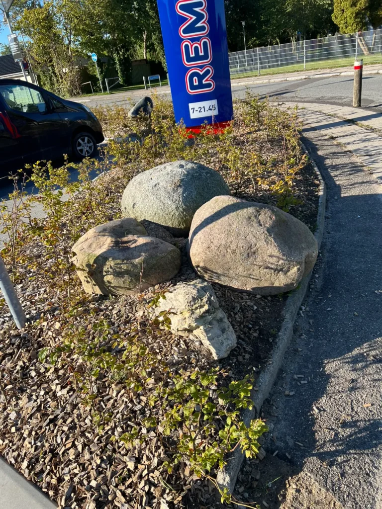 Bed med sten og buske ved parkeringsplads