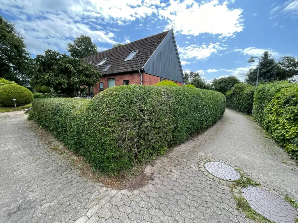 Rundklippet hæk ved et hus og en indkørsel